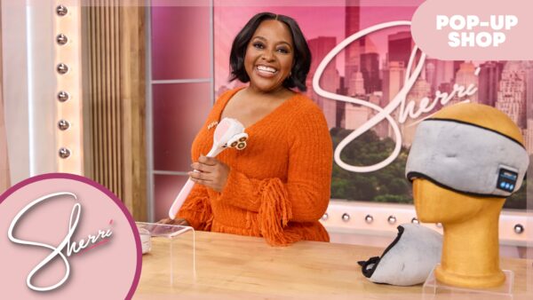 Sherri in orange dress holding product in front of a table full of products for sale