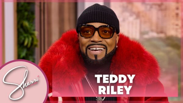 Close-up of singer Teddy Riley in furry red jacket, red sunglasses and black beanie hat
